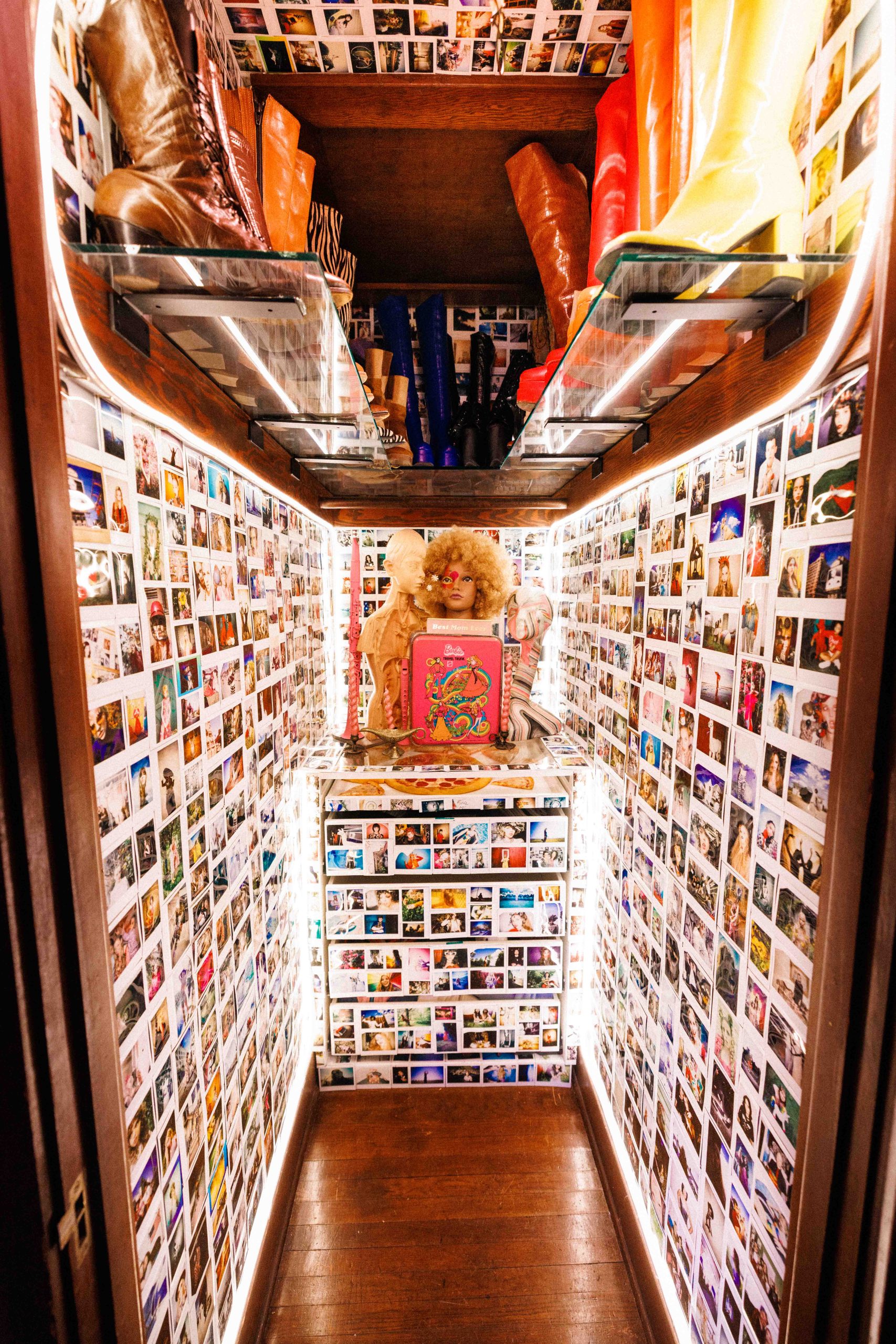 A narrow closet lined from floor to ceiling with photographs and shelves of collected objects.