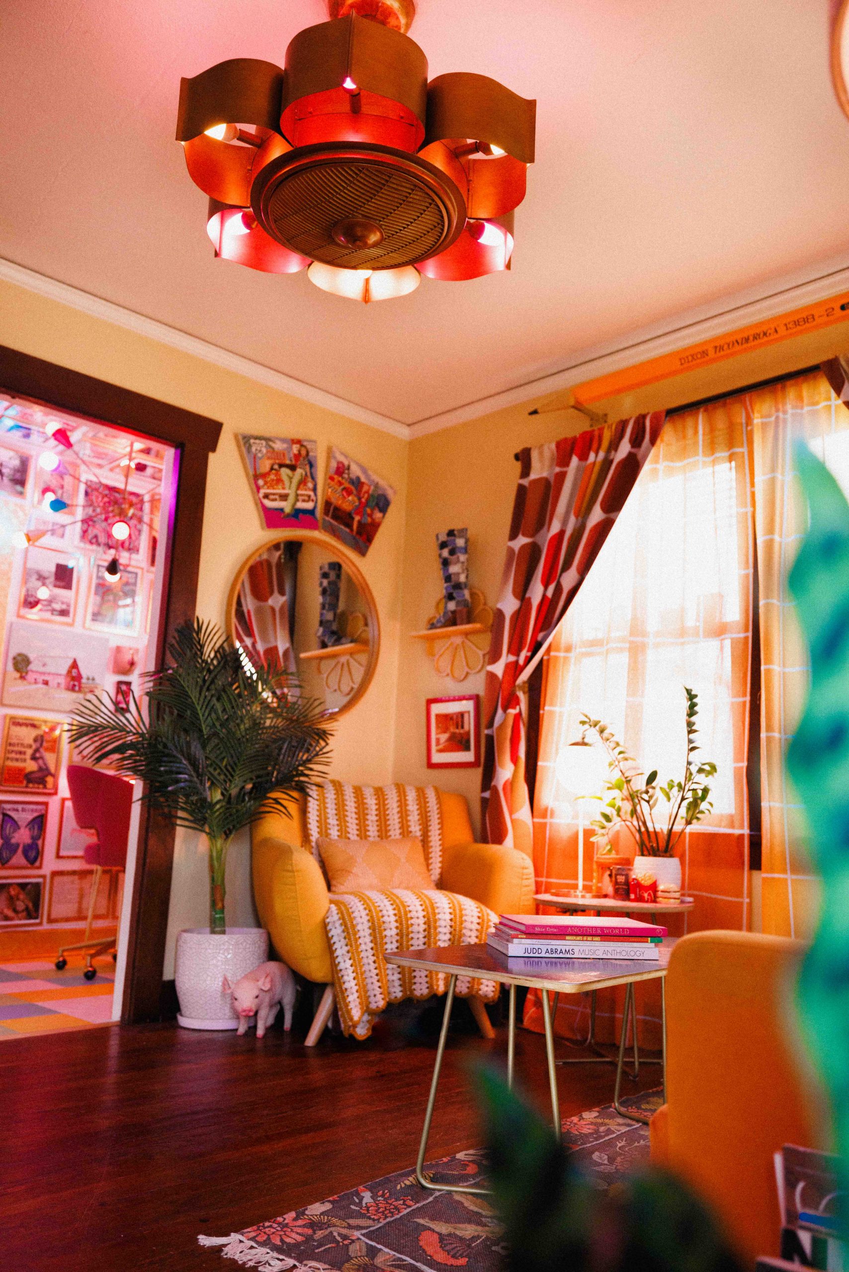 A living room with striped chairs, an orange sofa, bright curtains, and a red ceiling light.