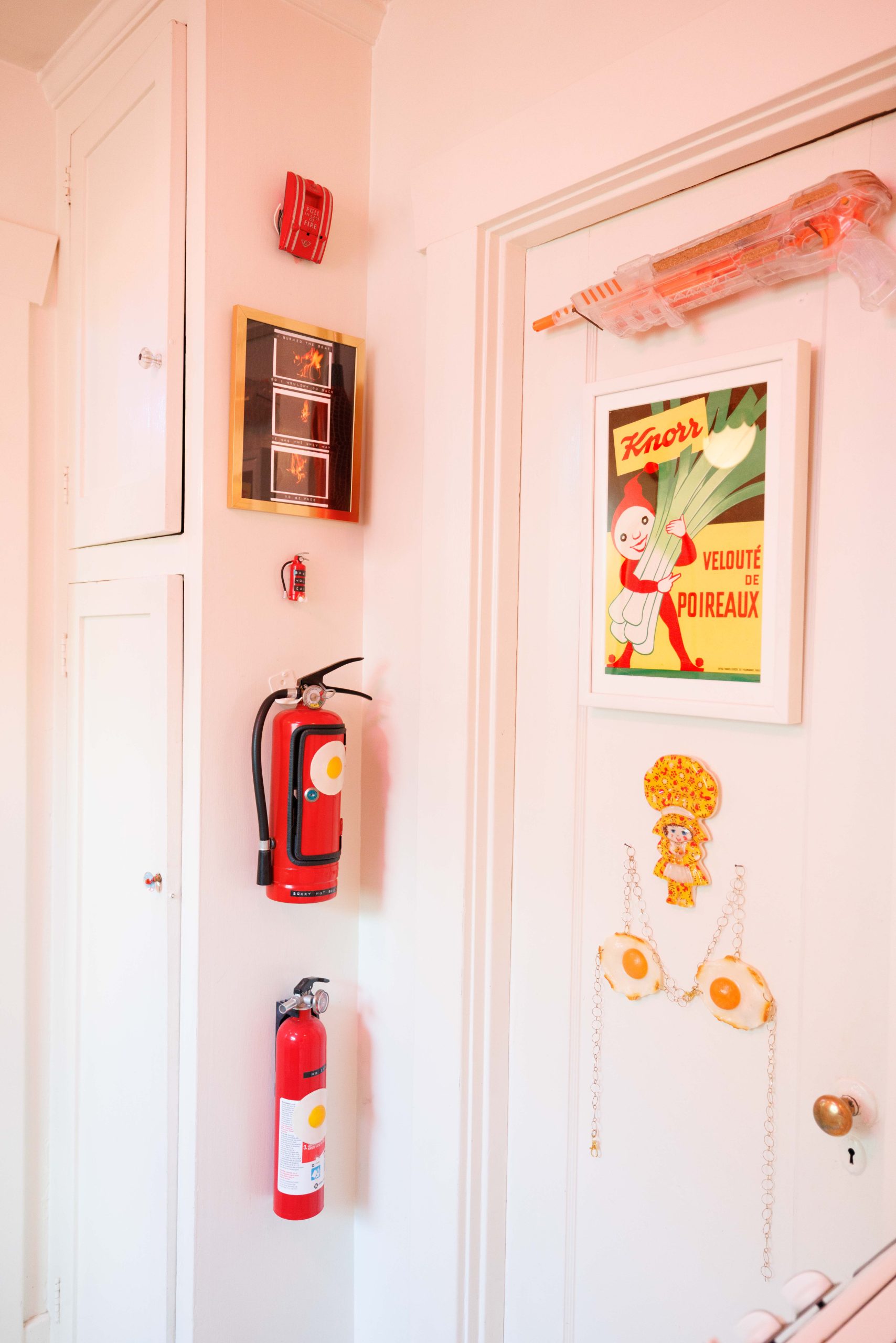 A pale door covered with small signs, with two fire extinguishers mounted alongside.