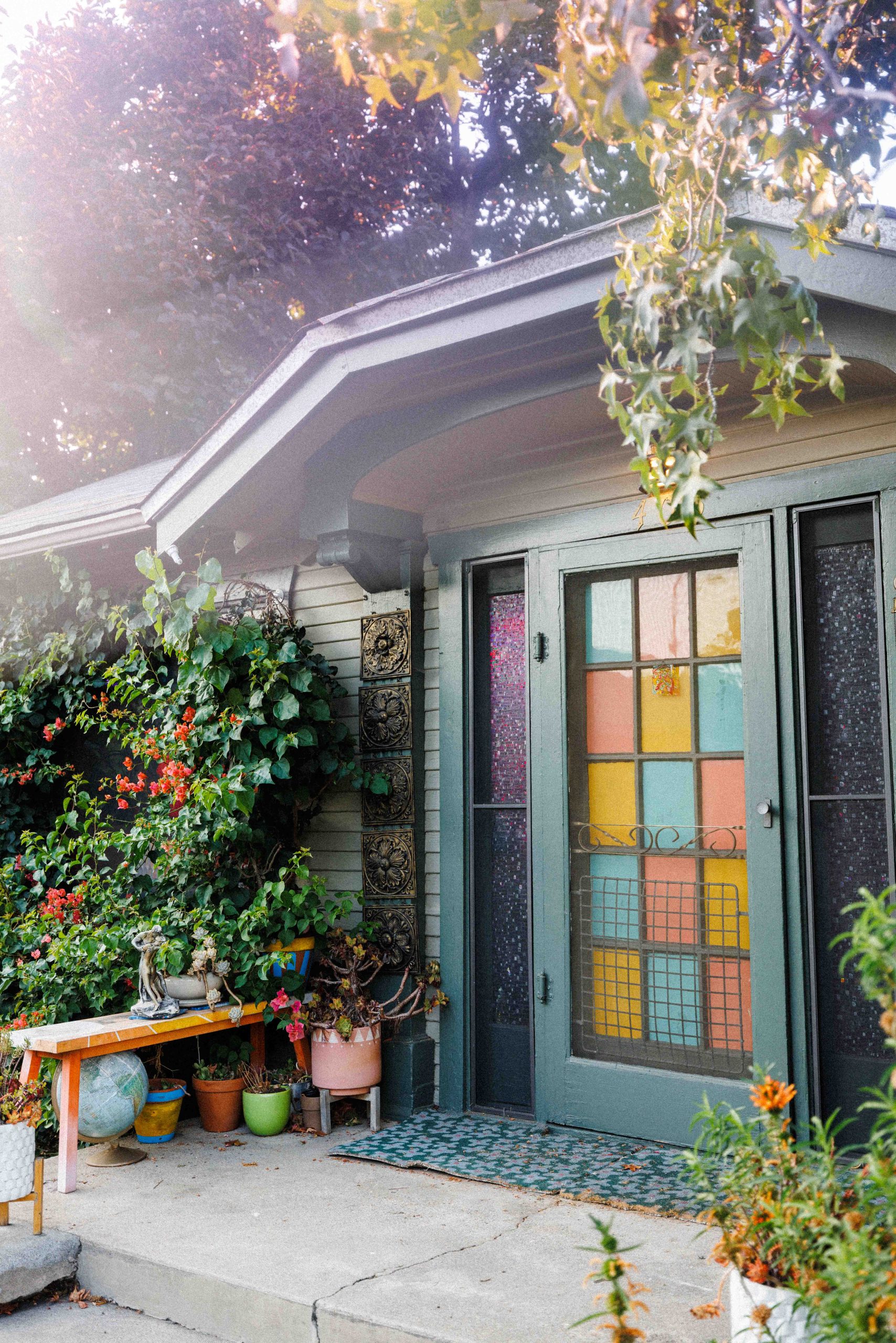 The Museum entrance, with colored glass door panels, potted plants, and overhanging branches.