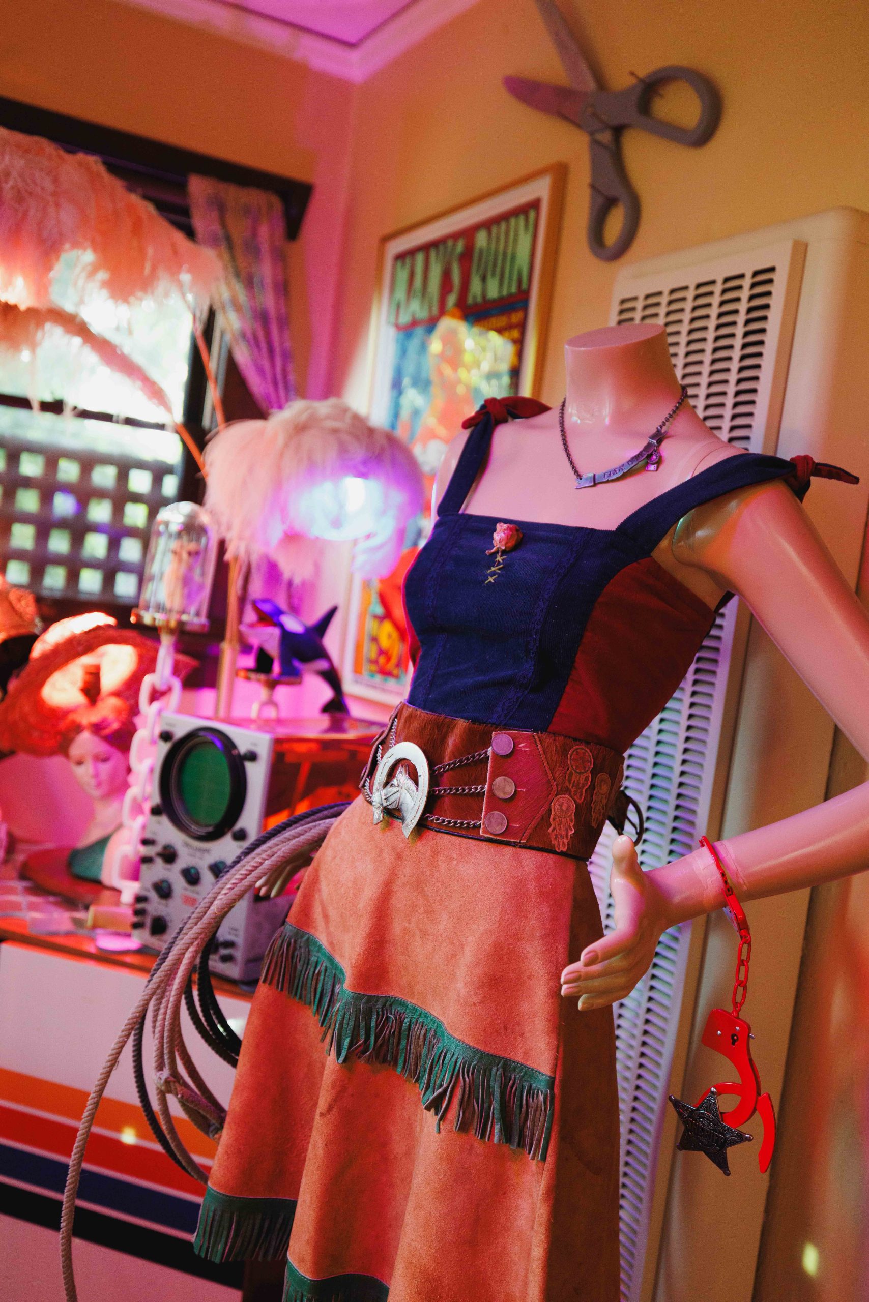 A torso mannequin in a dark top and patterned skirt wears a broad red belt.