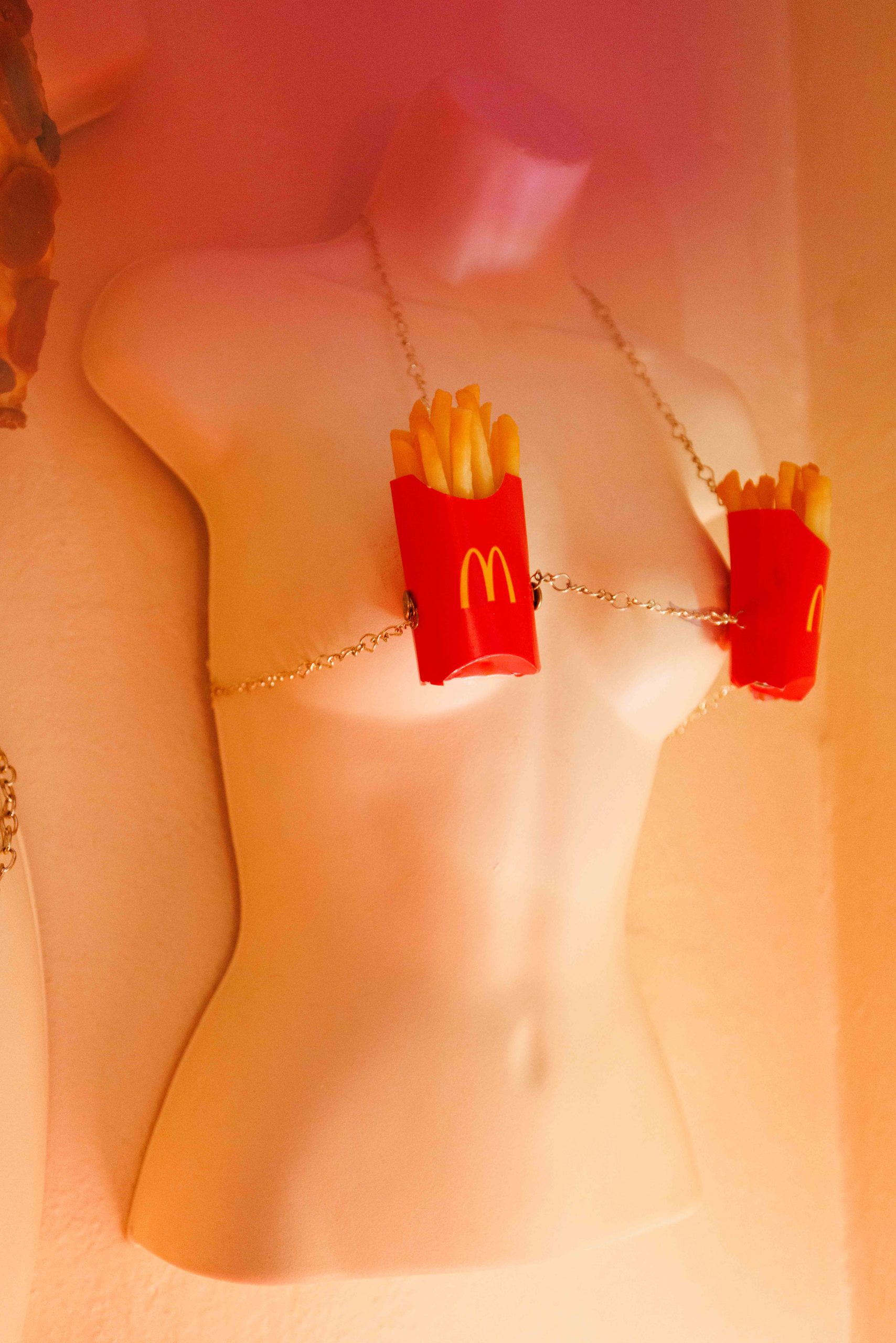 A torso mannequin wears a bikini top made from two cartons of replica French fries.