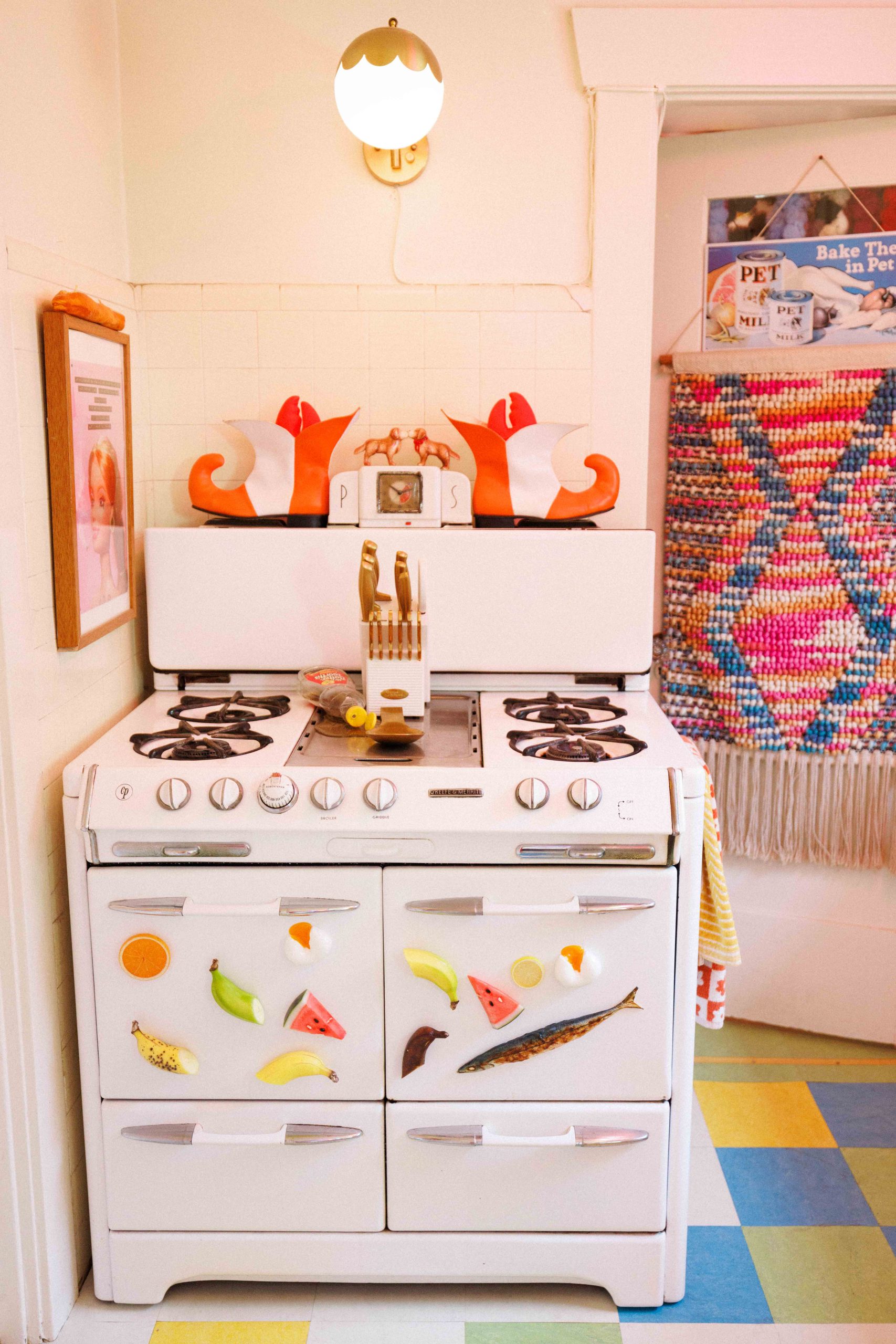 A white stove decorated with colorful food shapes beside a multicolored kitchen floor.