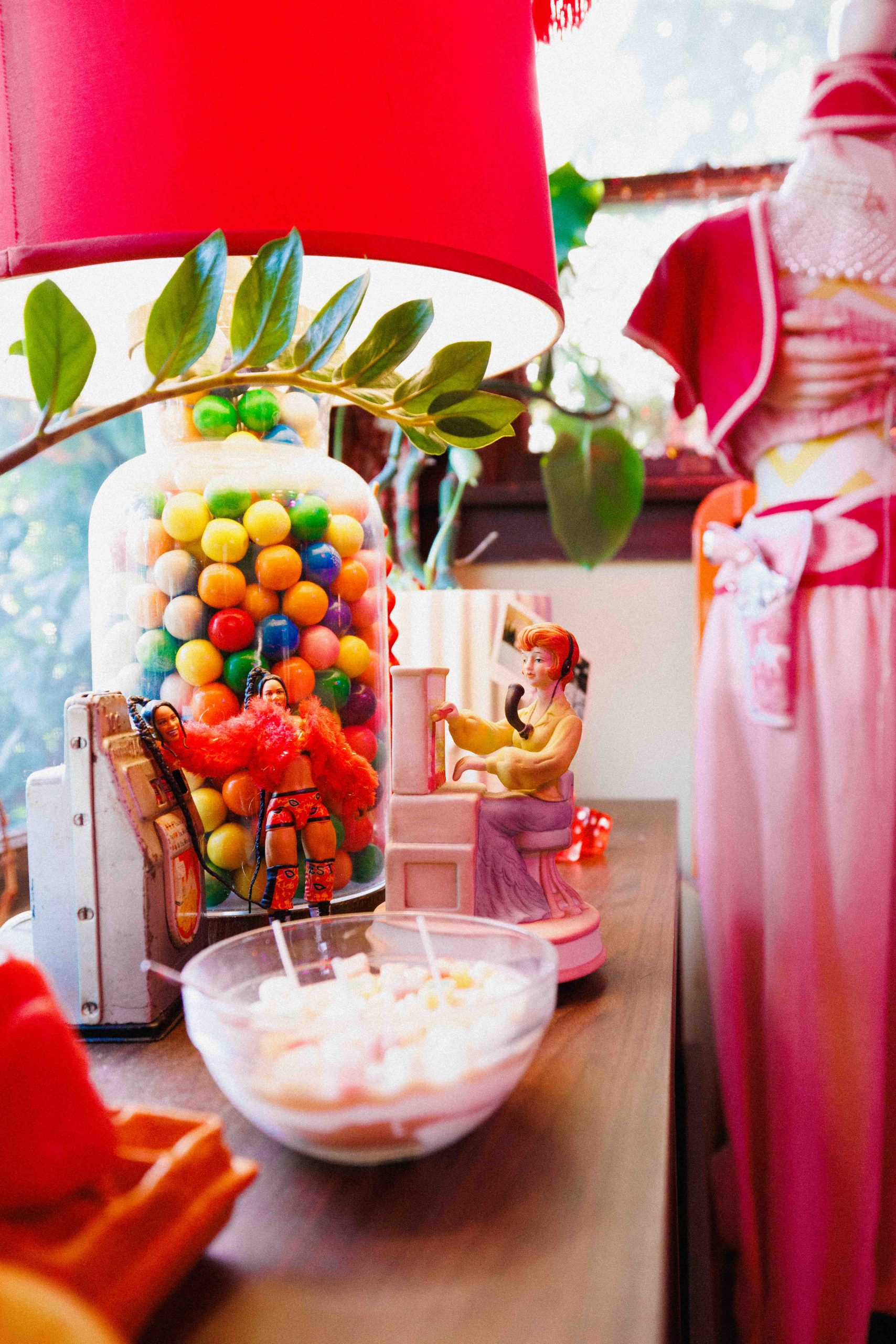 A red lamp above a jar of colorful balls and a bowl on a crowded countertop.